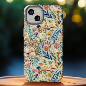 May include: A smartphone case with a floral and book design. The case features a light background with colorful flowers, open books, and green leaves. The case is made of a hard material and has a camera cutout.