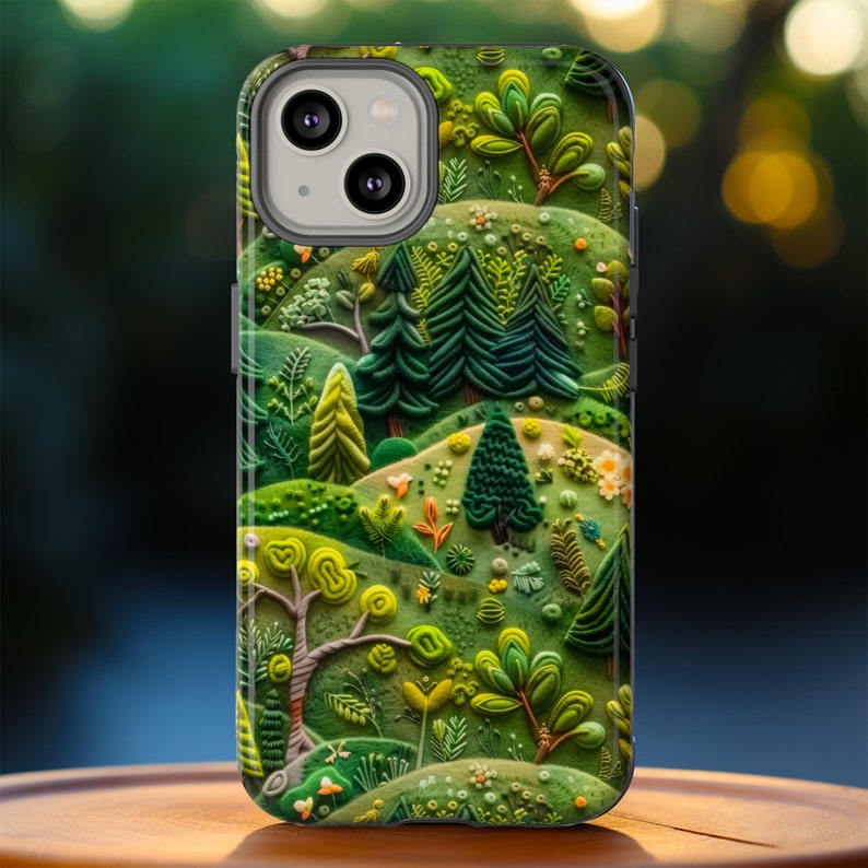 May include: A green, white and brown phone case with a 3D design of a forest scene. The case features trees, flowers and leaves.