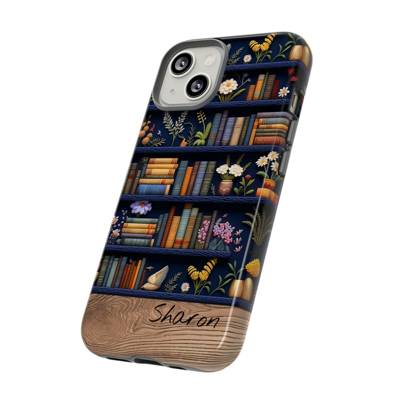 May include: A blue and brown phone case with a bookshelf design featuring books, flowers, and butterflies. The case has a wood-grain bottom with the name "Sharon" written on it.