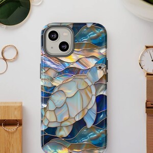 May include: A blue and gold iPhone case with a stained glass design of a sea turtle swimming in the ocean.