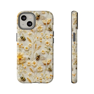 Könnte beinhalten: Eine weiße Handyhülle mit einem floralen Stickmuster mit gelben Blumen und schwarzen und gelben Bienen.