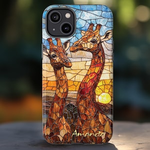 May include: A phone case with a stained-glass effect depicting two giraffes against a sunset. The giraffes are brown and tan, set against a blue and orange sky. The name "Amanda" is written in gold script at the bottom.