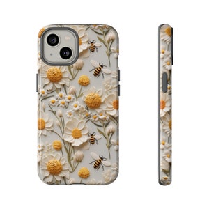 Pu&ograve; includere: Una custodia per iPhone bianca con un motivo floreale con margherite bianche e centri gialli. Le api sono sparse su tutto il design.