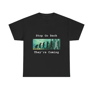 Op de afbeelding: Zwart T-shirt met een afbeelding van een rij stick figuren die de menselijke evolutie voorstellen. De tekst "Stop Go Back They're Coming" is op het T-shirt gedrukt.