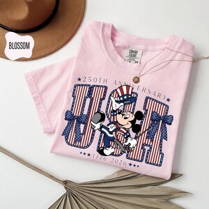 Mickey Mouse in patriotic attire with "USA 250th Anniversary 1776–2026" in stars and stripes on a t-shirt.