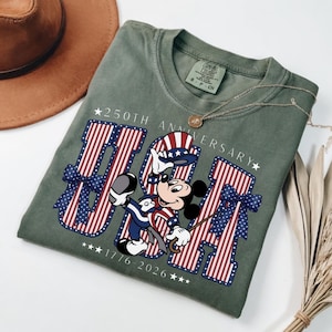 Retro Mickey Mouse in patriotic attire with "USA" and "250th Anniversary 1776–2026" on a t-shirt.