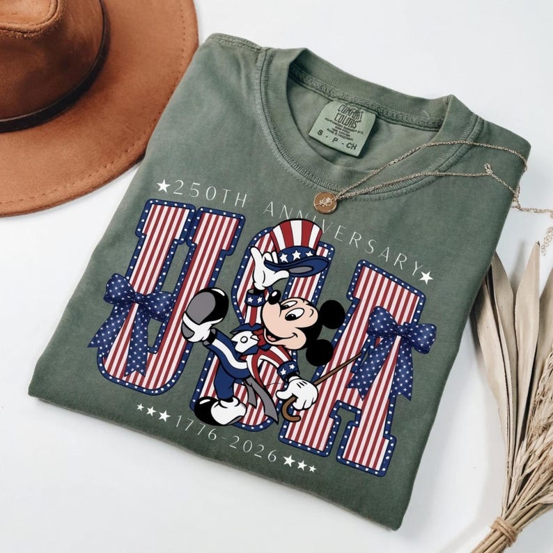 Retro Mickey Mouse in patriotic attire with "USA" and "250th Anniversary 1776–2026" on a t-shirt.