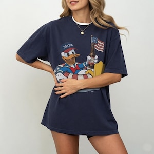 A woman wearing a navy blue t-shirt with a cartoon image of a duck holding an American flag.