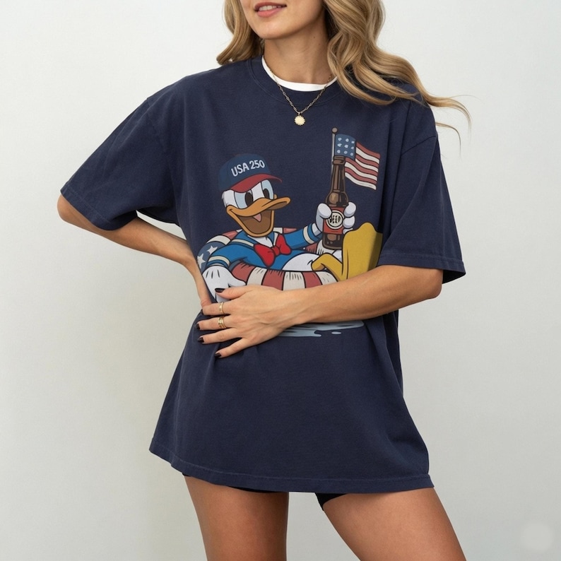 A woman wearing a navy blue t-shirt with a cartoon image of a duck holding an American flag.