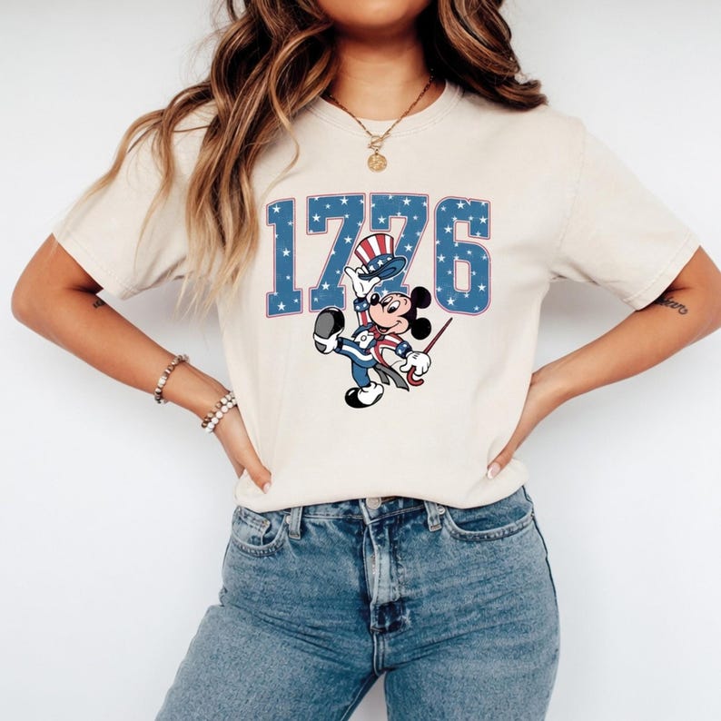 Patriotic Mickey Mouse in Uncle Sam attire with "1776" text featuring stars and stripes on a t-shirt.