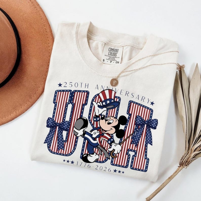 Retro Mickey Mouse in patriotic attire with "USA" and "250th Anniversary 1776–2026" on a t-shirt.
