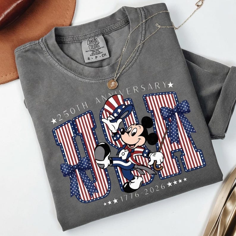 Mickey Mouse in patriotic attire with "USA" text and stars and stripes design on a t-shirt.