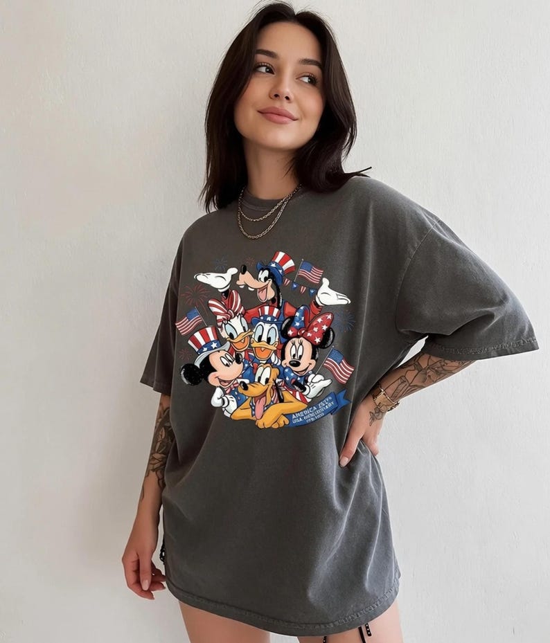 Mickey and Friends in patriotic hats with American flags, celebrating Independence Day 2026 on a t-shirt.