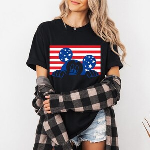 Patriotic design with a character silhouette against American flag stripes and stars on a t-shirt.