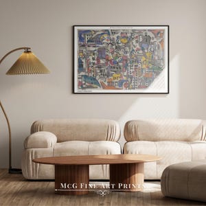 May include: A colorful abstract painting of a city scene with buildings, streets, and vehicles. The painting is framed in black and hangs on a beige wall above a light brown couch and coffee table. The text "The Museum of Modern Art New York 1939" is printed at the top of the painting.