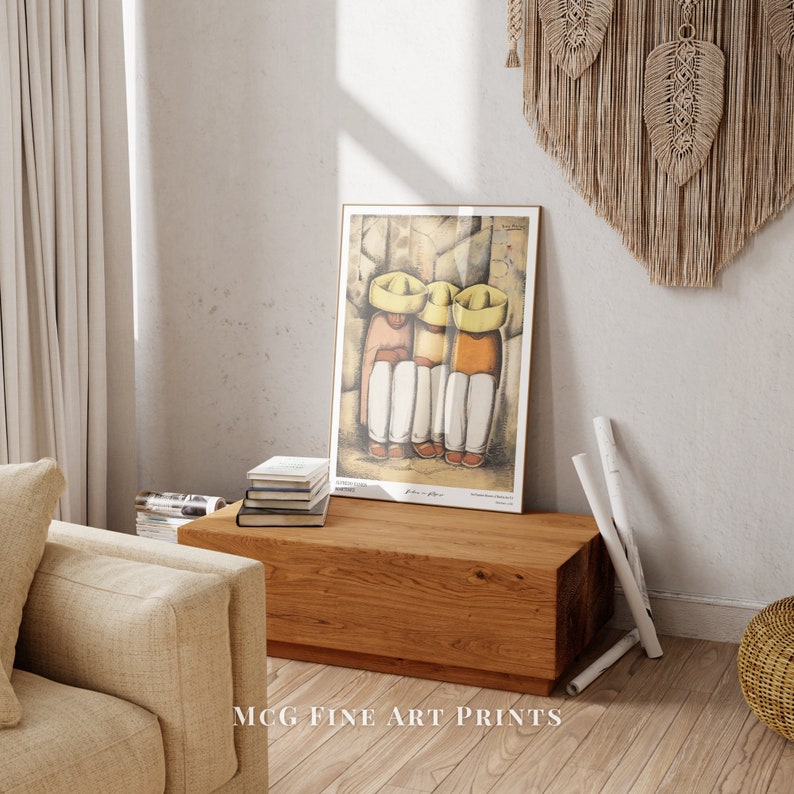 May include: A framed print of a painting depicting three people wearing yellow hats, sitting together. The painting is in a rustic style and features warm colors. The print is hanging on a wall above a wooden shelf with books and a white vase.