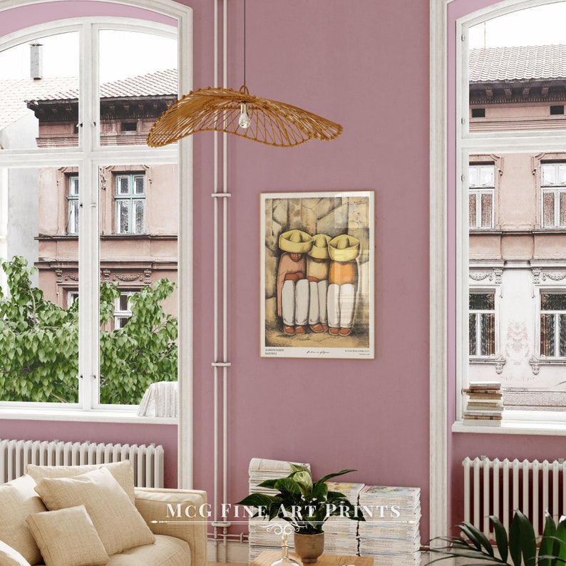 May include: A framed print of a painting depicting three figures wearing yellow hats and traditional clothing. The painting is set against a pink wall with a woven lampshade hanging above it.