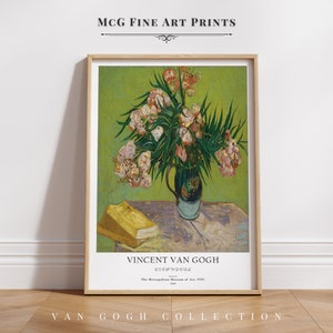 Puede incluir: Una impresión enmarcada de una pintura de Vincent van Gogh titulada "Adelfas". La pintura representa un jarrón de flores de adelfa rosas con hojas verdes sobre una mesa con un libro amarillo. El texto "VINCENT VAN GOGH" y "OLEANDERS" está impreso debajo de la pintura.