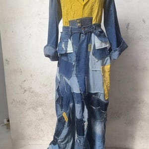 May include: A long-sleeved dress featuring a mustard yellow textured bodice with a notched lapel collar, combined with a floor-length skirt constructed from various shades of blue denim patches, including pockets, seams, and frayed edges.
