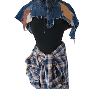 May include: A denim and brown patchwork hooded cape with a black shirt and a blue and brown plaid shirt tied around the waist.