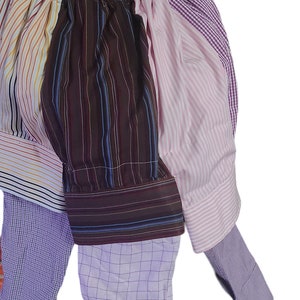 May include: A patchwork shirt made from different patterned fabrics in shades of pink, purple, brown, and white. The shirt has a gathered neckline and long sleeves.