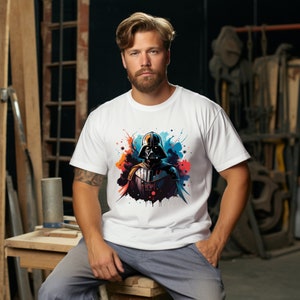 Op de afbeelding: Wit T-shirt met een kleurrijke afbeelding van Darth Vader. Het ontwerp bevat een zwarte helm en borstplaat met levendige spetters van oranje, blauw en rood. Het T-shirt is gemaakt van zacht materiaal en heeft korte mouwen.