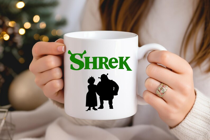 May include: White ceramic mug with a green "Shrek" logo and a black silhouette of Shrek and Fiona.