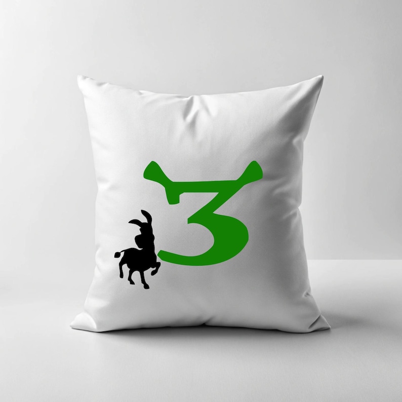 May include: White pillow with a green number 3 and a black silhouette of a donkey. The number 3 is stylized to look like the ogre's ears.
