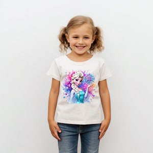 May include: White t-shirt with a colorful watercolor design featuring a cartoon image of Elsa from Frozen. Elsa is wearing a blue and silver dress and holding a snowflake.