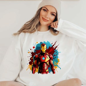 May include: White sweatshirt with a colorful graphic of Iron Man in a red and gold suit with a blue and yellow background.