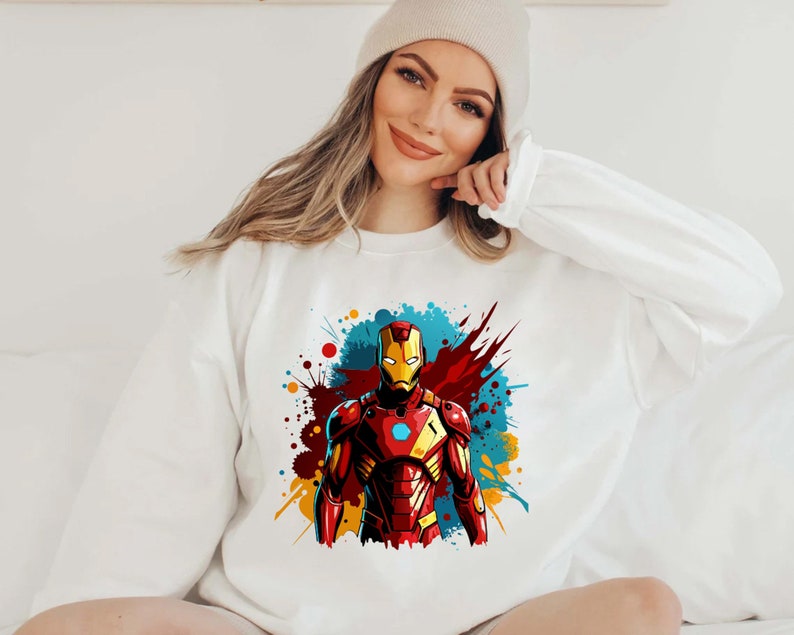 May include: White sweatshirt with a colorful graphic of Iron Man in a red and gold suit with a blue and yellow background.