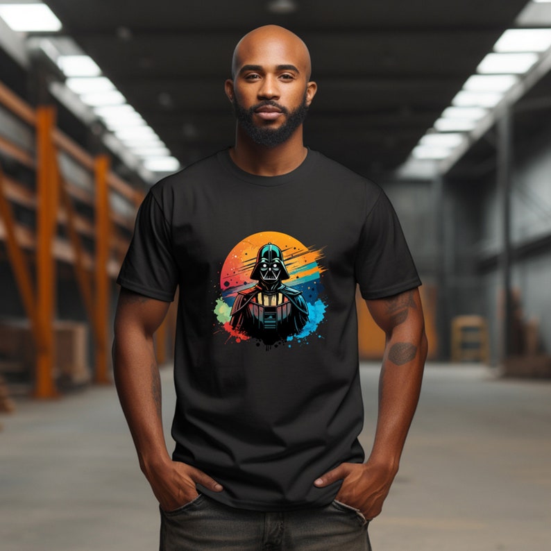 Op de afbeelding: Zwart t-shirt met een kleurrijke afbeelding van Darth Vader. Het ontwerp bevat een levendige zonsondergang-achtige achtergrond met verfspattereffecten. De illustratie toont de helm en borstplaat van het personage.