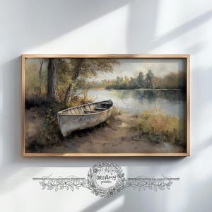 Könnte beinhalten: Gerahmter Kunstdruck mit einer ruhigen See-Szene und einem kleinen, verwitterten Boot am Ufer. Das Kunstwerk ist in gedämpften Grün-, Braun- und Grautönen gehalten und strahlt Ruhe aus. Der Rahmen besteht aus hellem Holz.