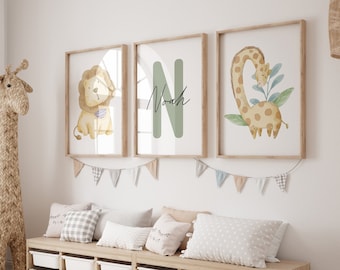 Könnte beinhalten: Drei gerahmte Drucke mit einer Aquarell-Illustration eines Löwen, einer Giraffe und dem Buchstaben N mit dem Namen Noah in Kursivschrift. Die Drucke hängen an einer weißen Wand über einer Holzbank mit Aufbewahrungskisten.