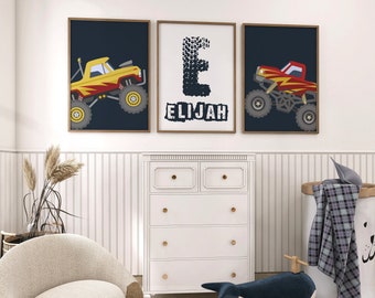 May include: Three framed prints with a monster truck theme. The center print features the letter "E" made of tire tracks and the name "Elijah" below it. The prints on either side feature a yellow and red monster truck on a dark blue background.