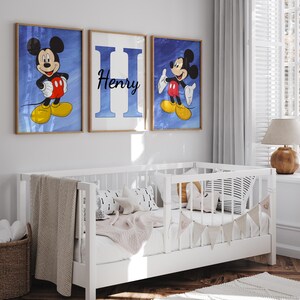Op de afbeelding: Drie ingelijste prints met een blauwe achtergrond. De middelste print heeft de letter "H" in wit met de naam "Henry" in zwart. De prints aan weerszijden tonen Mickey Mouse in een rood en geel outfit tegen een blauwe achtergrond.