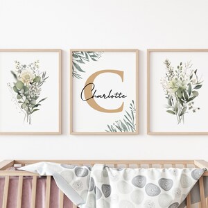 May include: Three framed prints with a watercolor floral design. The center print features a large gold letter "C" with the name "Charlotte" written in cursive below it. The prints are perfect for a nursery or child's room.