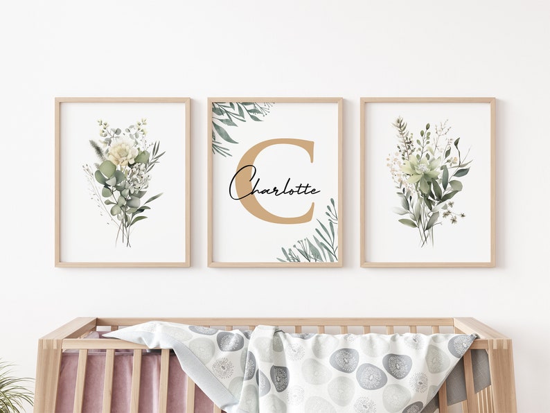 May include: Three framed prints with a watercolor floral design. The center print features a large gold letter "C" with the name "Charlotte" written in cursive below it. The prints are perfect for a nursery or child's room.
