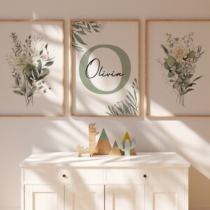 May include: Three framed prints with a green and white floral design. The middle print features the letter "O" with the name "Olivia" written inside the circle.