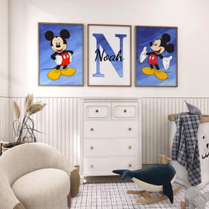 Op de afbeelding: Drie ingelijste prints met Mickey Mouse op een blauwe aquarel achtergrond. De middelste print heeft de letter "N" met de naam "Noah" eronder.