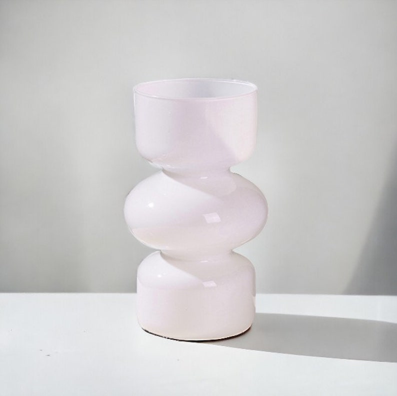 Peut inclure: Un vase en c&eacute;ramique blanc avec un design arrondi et bulbeux. Le vase a une finition lisse et brillante et est parfait pour pr&eacute;senter des fleurs ou de la verdure.