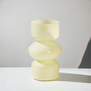 Peut inclure: Un vase en verre jaune p&acirc;le avec un design unique, arrondi et &agrave; trois niveaux.