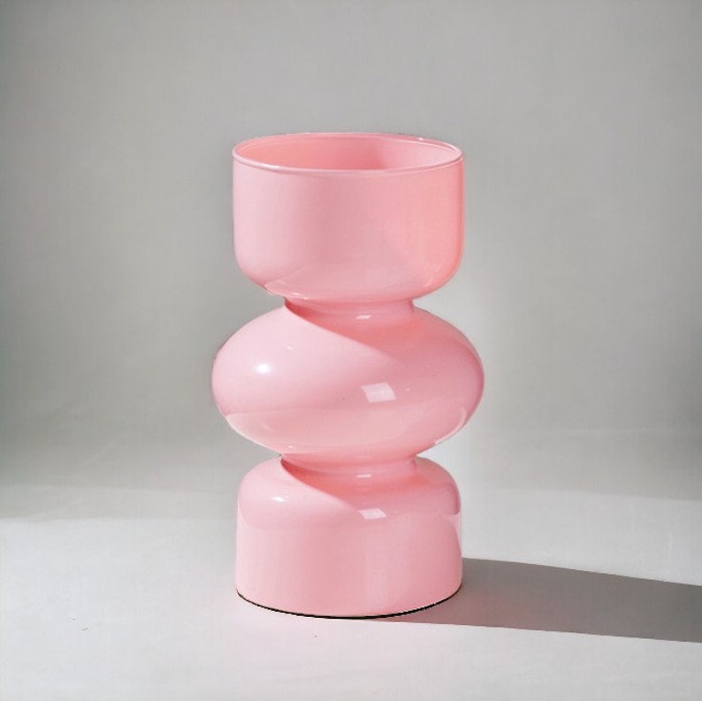 Peut inclure: Un vase en verre rose avec un design unique et bulbeux. Le vase est compos&eacute; de trois sections, chacune avec une forme arrondie. Le vase est parfait pour ajouter une touche de style moderne &agrave; n'importe quelle maison.