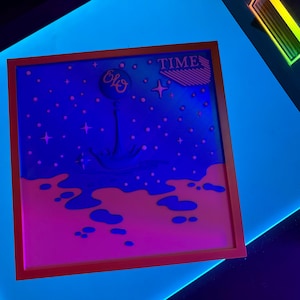 May include: A framed artwork with a vibrant, neon color scheme. The image features a blue and pink landscape with the word "TIME" and the letters "ELO". The artwork is set against a bright blue background.