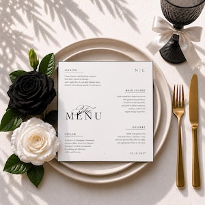 Puede incluir: Una tarjeta de menú cuadrada blanca con texto negro que presenta secciones para entrante, plato principal, bodega y postre, colocada sobre platos de cerámica apilados. El menú incluye el texto The Menu, N | L y 15.10.2027, junto a una rosa negra y blanca.