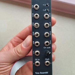 Pode incluir: Módulo eletrônico preto com a inscrição "Thresh", equipado com vários conectores de entrada, botões e o texto "Timo Rozendal". O módulo tem números e etiquetas para várias funções, incluindo "CV in" e "Clock".