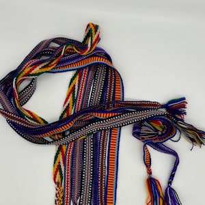 Pu&ograve; includere: Una collezione di nastri colorati tessuti con motivi intricati e nappe. I nastri presentano una variet&agrave; di colori, tra cui rosso, giallo, blu e verde, e sono probabilmente utilizzati per scopi decorativi o artigianali.