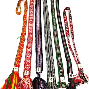May include: Seven long, narrow woven fabric belts or sashes, each featuring distinct geometric patterns and color combinations, including red, yellow, green, black, white, and grey, with numbered tags and fringed ends at the bottom of each.