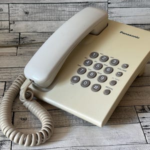 Panasonic landline phone. Panasonic KX-TS2350UA phone. Landline phone. Push-button phone. Landline phone. White phone. Phone integrated.
