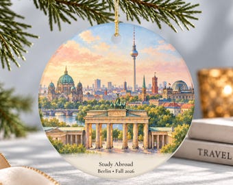 May include: A round ceramic ornament featuring a detailed illustration of the Berlin skyline, including the Brandenburg Gate and the TV Tower. The text Study Abroad Berlin Fall 2026 is printed at the bottom. It includes a gold hanging string.
